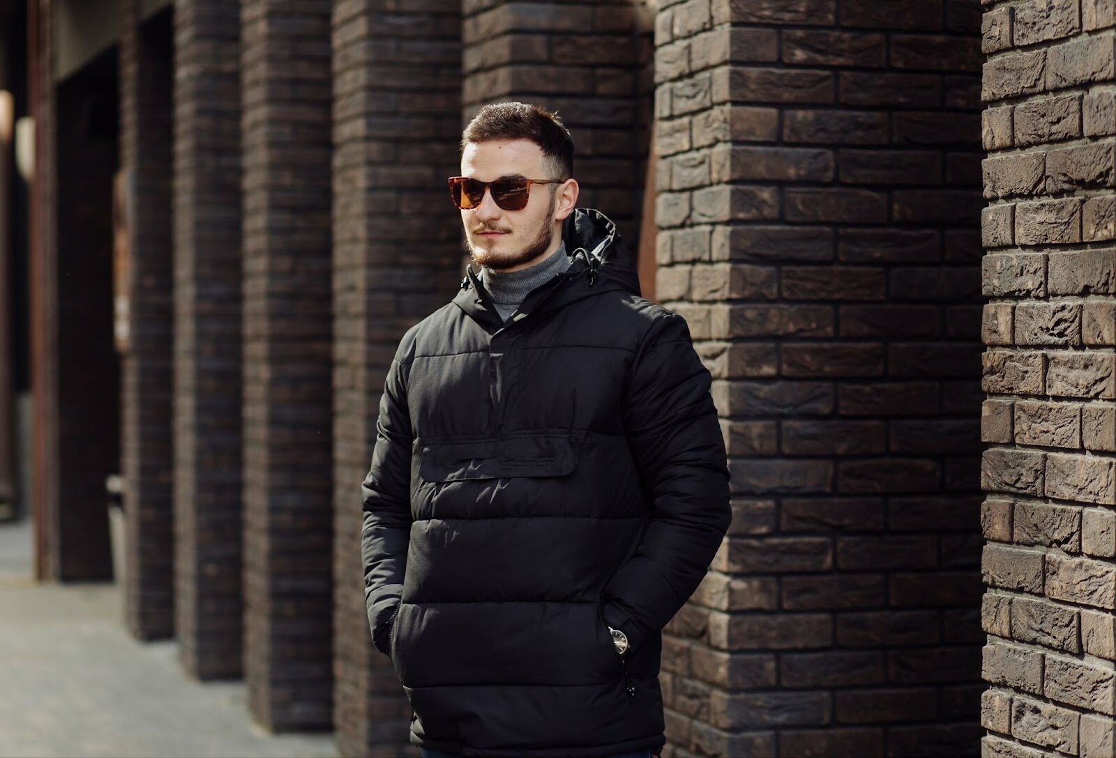 positive smiling young male in stylish clothes standing outside alone near wall of urban building and speaking on mobile phone 65797c1b9c363